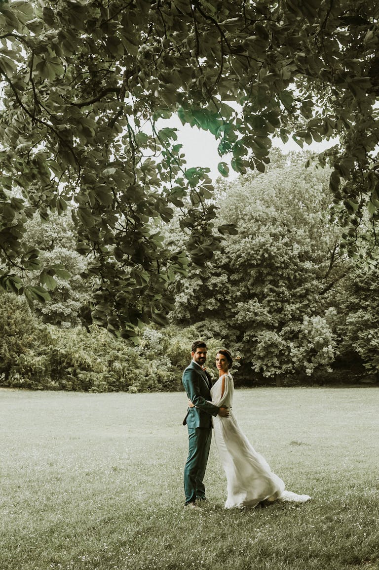 Elegant wedding couple in a lush park setting, capturing love and elegance.